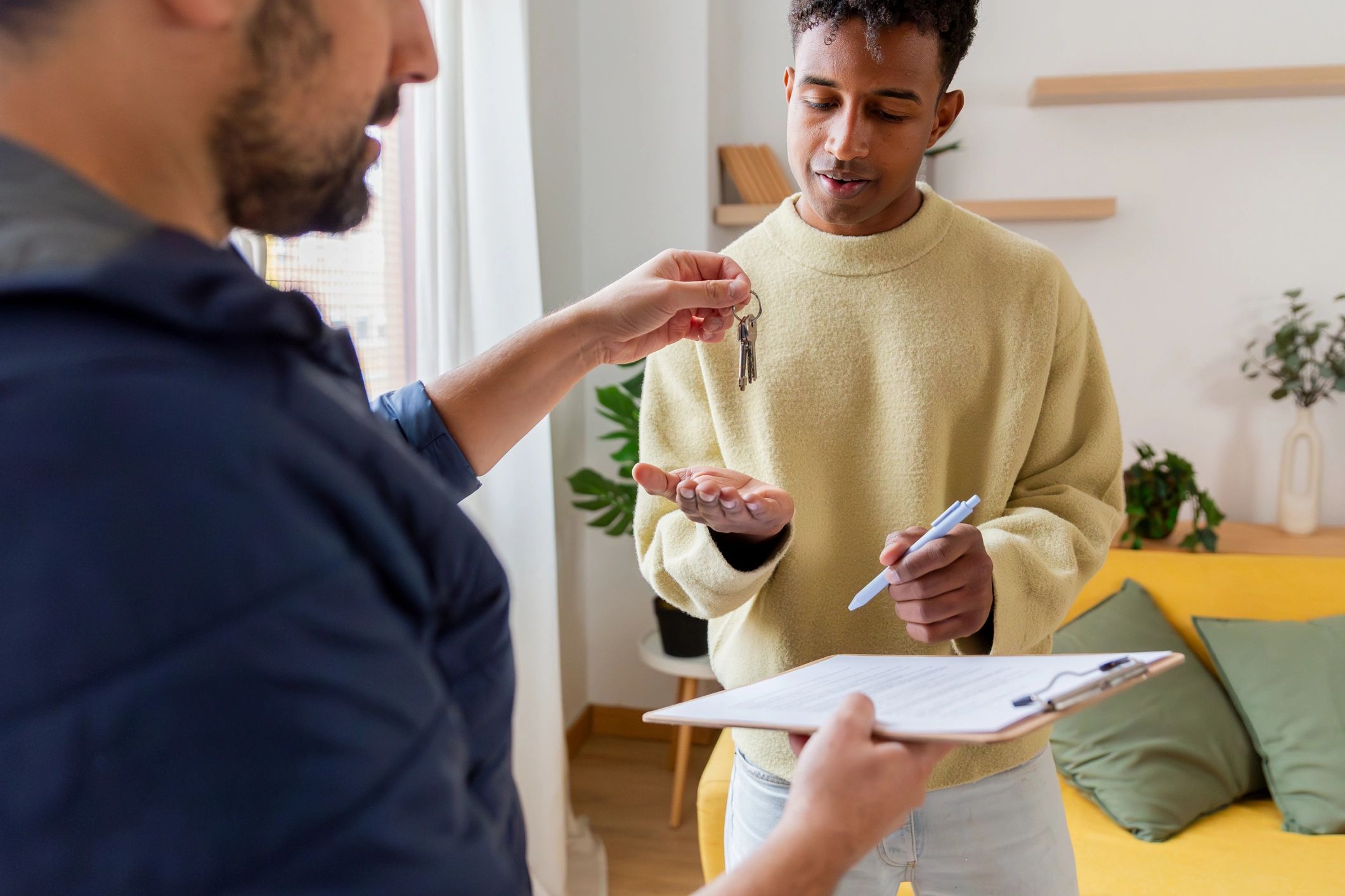 Landlord and tenant signing paperwork with keys on the table